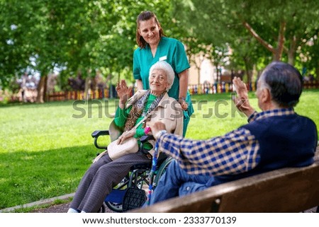 An elderly woman, full of joy and happiness, sits in a wheelchair, warmly greeting her elderly friend on a sunny day.