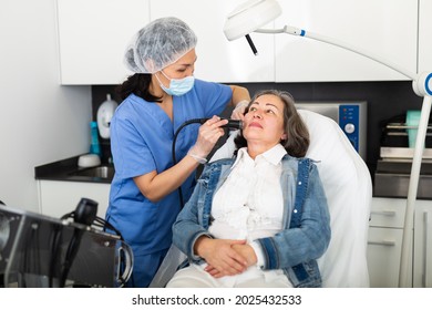 Elderly Woman Getting Facial Electroporation Procedure From Experienced Cosmetologist In Aesthetic Medicine Office.