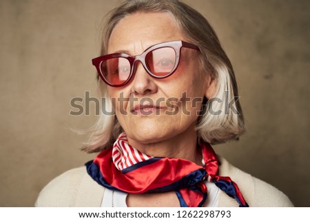 Elderly woman in glasses with a red scarf around her neck                    