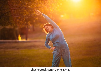 An elderly woman goes in for sports at sunset. Exercises for stretching