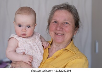 Elderly Woman Grandmother Holding A 7 Month Baby In Her Arms At Home