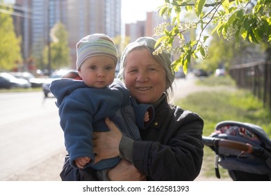 Elderly Woman Grandmother Holding A 9 Month Baby In Her Arms