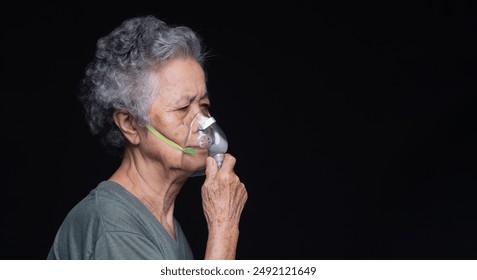 Elderly woman with gray hair wearing an oxygen mask against a dark background represents health care and respiratory assistance. Perfect for themes of aging and medical support. - Powered by Shutterstock