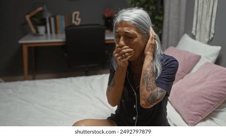 Elderly woman with grey hair coughing on a bed in a cozy bedroom with a study desk in the background, showcasing a home interior setting. - Powered by Shutterstock