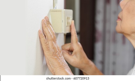 Elderly Woman Hand Turning On The Light With A Wall Switch