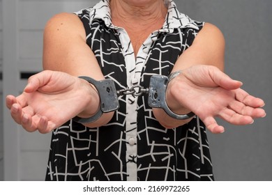 An Elderly Woman In Handcuffs On A Blurry Background In An Apartment. An Elderly Criminal, Criminal Liability Of Pensioners, Domestic Violence Against Women.