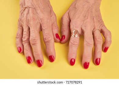 Elderly Woman Hands With Red Manicure. Senior Woman Hands With Red Nails On Yellow Background. Old Woman Hands With Perfect Red Manicure.