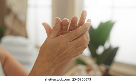 Elderly woman hands in a spa room with blurred background, suggesting a serene and relaxing wellness experience indoors. - Powered by Shutterstock