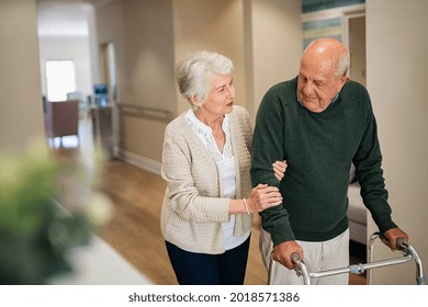 Elderly woman help her husband walking using walker in nursing home. Senior woman helping disabled man with walking frame. Lovely wife holding hands of old husband in care centre.