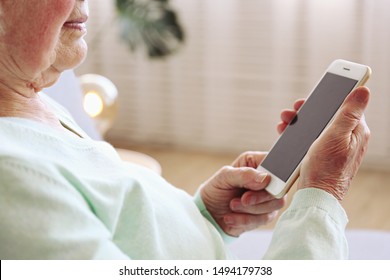 Elderly Woman Holding Blank Screen Cell Phone Gadget In Hands. Old Lady With Wrinkled Skin Trying To Vigure Out Touchscreen Smartphone. Background, Close Up, Overhead, Top View, Copy Space.