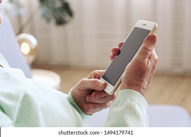 Elderly Woman Holding Blank Screen Cell Phone Gadget In Hands. Old Lady With Wrinkled Skin Trying To Vigure Out Touchscreen Smartphone. Background, Close Up, Overhead, Top View, Copy Space.