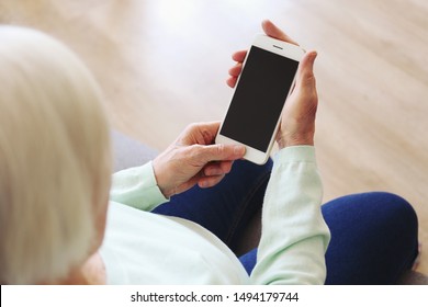 Elderly Woman Holding Blank Screen Cell Phone Gadget In Hands. Old Lady With Wrinkled Skin Trying To Vigure Out Touchscreen Smartphone. Background, Close Up, Overhead, Top View, Copy Space.