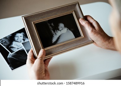 An elderly woman is holding a frame with a black and white  photo. Sentimentality on father's day. - Shutterstock ID 1587489916