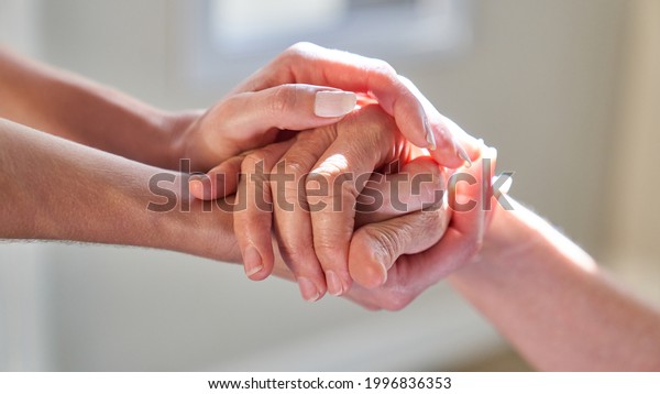 Elderly woman holding hands as a\
symbol of support and assistance in the hospice with\
euthanasia
