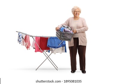 Elderly Woman Holding A Laundry Basket With Clothes Next To A Clothing Line Rack Isolated On White Background