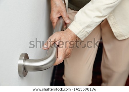 Elderly woman holding on handrail for safety walk steps