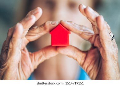 Elderly woman holding a small house in her hands