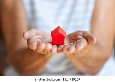 Elderly Woman Holding A Small House In Her Hands