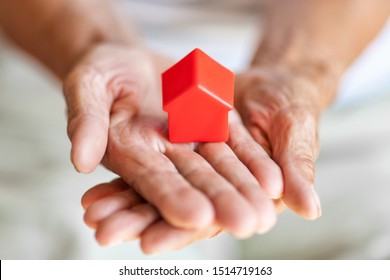 Elderly woman holding a small house in her hands