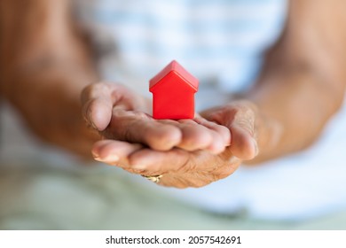 Elderly woman holding a small house in her hands - Shutterstock ID 2057542691