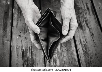 An Elderly Woman Holds An Empty Purse Or Wallet On Wooden Vintage Table. Black And White Photo.The Concept Of Poverty In Retirement. Global Extreme Poverty. No Money Help Me. Global Financial Crisis.