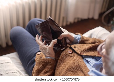 Elderly woman holds in his hands an empty wallet. Vintage empty purse in wrinkled hands . Poverty in retirement concept