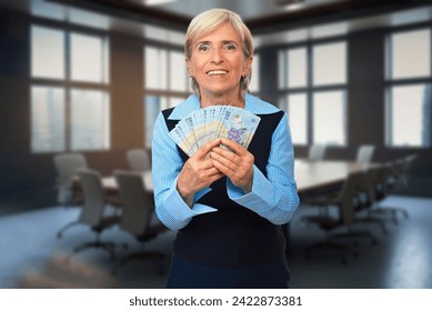 An elderly woman holds Romanian money in a conference room, symbolizing financial discussions and diverse perspectives in business - Powered by Shutterstock