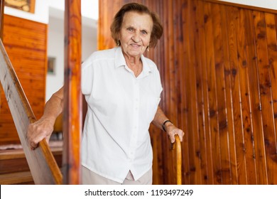 Elderly Woman At Home Using A Walking Cane To Get Down The Stairs