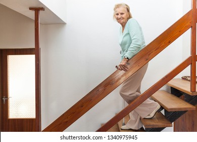 Elderly Woman At Home Using A Walking Cane To Get Down The Stairs