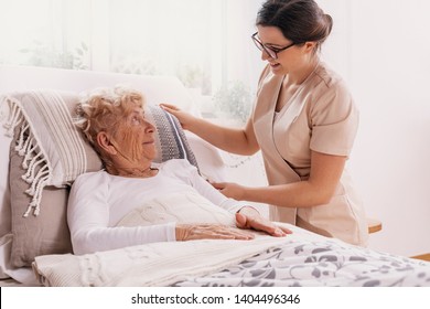 Elderly Woman In Hospital Bed With Social Worker Helping Her