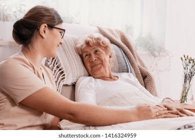 Elderly Woman In Hospital Bed With Social Worker Helping Her