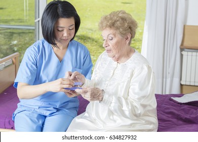 Elderly woman at hospital taking medical pill from asian nurse.