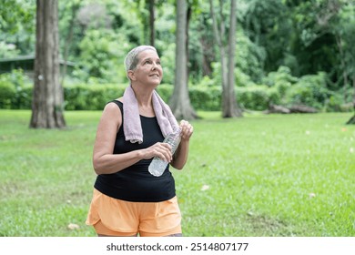 Elderly woman hydrating after workout in park - Powered by Shutterstock