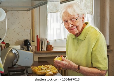 Elderly Woman in the Kitchen Peeling Potatoes 
