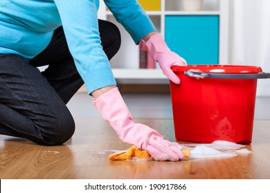 Elderly woman kneeling, doing floor cleaning at home