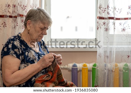 an elderly woman knitting sitting by the window