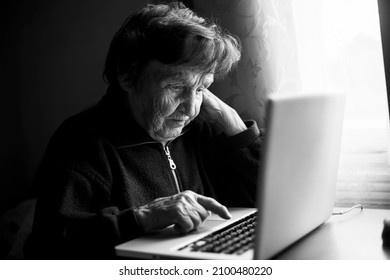 Elderly Woman Learns To Work At Her Computer At Home. Black And White Photo.