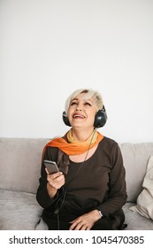 Elderly woman listening to music and smiling. The older generation and new technologies