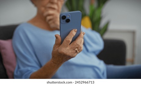 Elderly woman in a living room thoughtfully using smartphone - Powered by Shutterstock