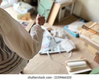 Elderly Woman Looking At A Photo Album During Decluttering