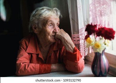 Elderly Woman Looks Sadly Out The Window.