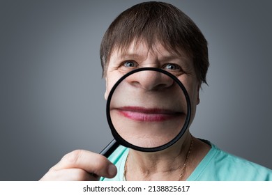 Elderly Woman With A Magnifying Glass In Her Hands.