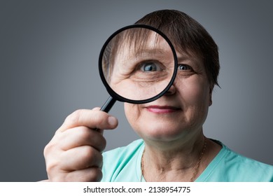 Elderly Woman With A Magnifying Glass In Her Hands.