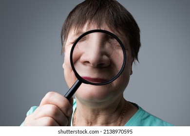 Elderly Woman With A Magnifying Glass In Her Hands.