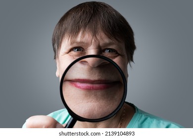 Elderly Woman With A Magnifying Glass In Her Hands.