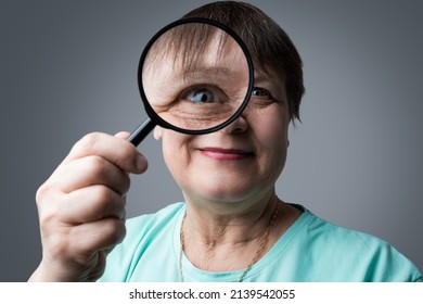 Elderly Woman With A Magnifying Glass In Her Hands.