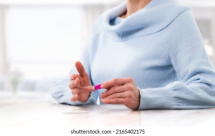Elderly woman making fingertip covid blood test at home front view