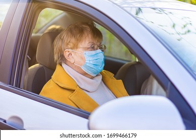 An Elderly Woman In A Medical Face Mask On The Passenger Seat In The Car. Driving To The Hospital During Coronavirus Pandemic Concept. Road Trip, Travel And Old People Concept - Happy Senior Couple