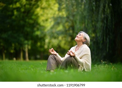 Elderly woman meditating in the summer park - Powered by Shutterstock