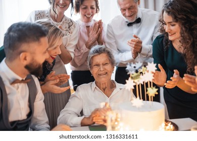 An Elderly Woman With Multigeneration Family Celebrating Birthday On Indoor Party.